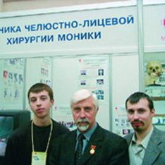 Александр Александрович Никитин с сыновьями на международной выставке в Москве на фоне стенда достижений руководимого им отделения